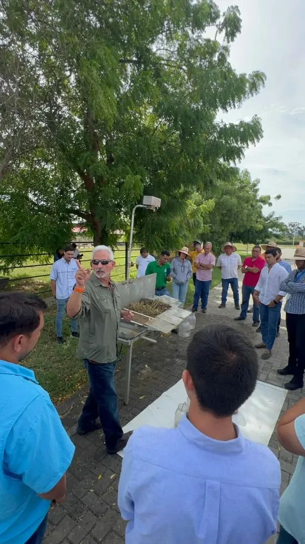 Un técnico explica una muestra de suelo a un grupo de productores, al aire libre.